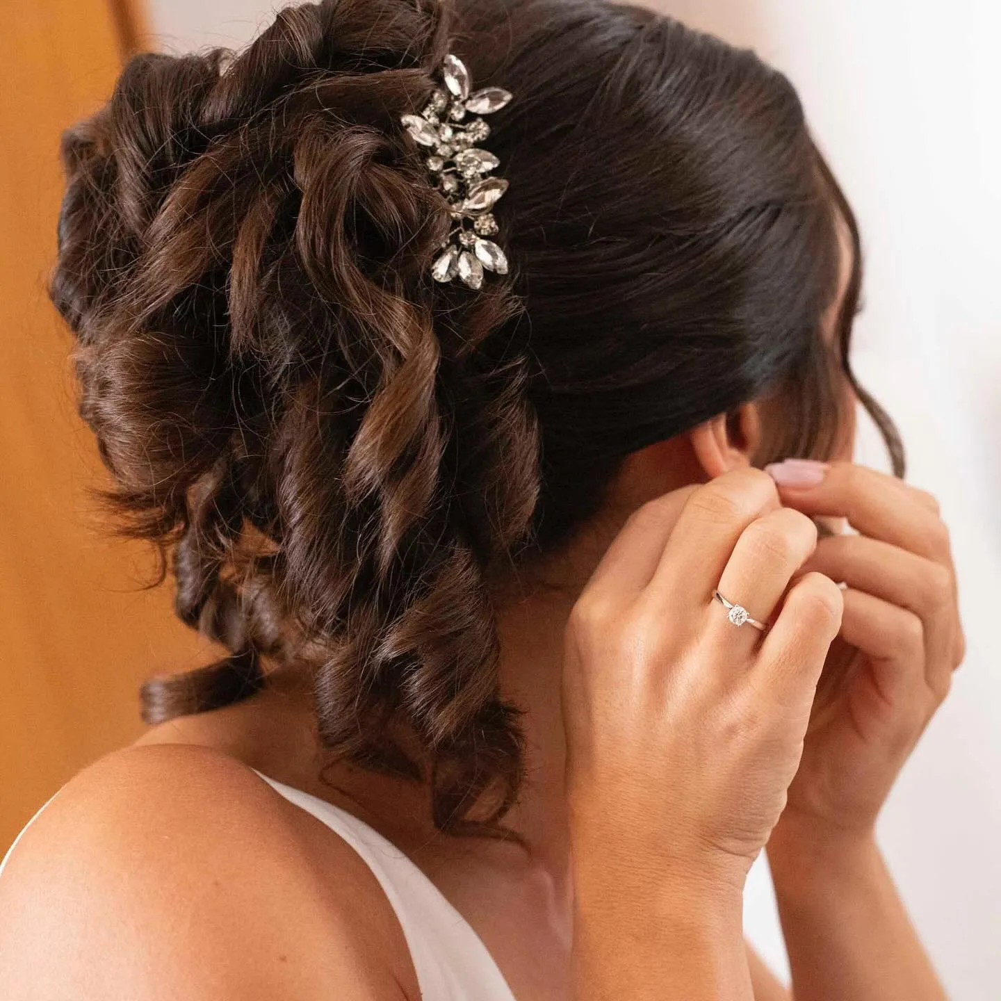 Raccolto da sposa con ricci morbidi e gioiello tra i capelli