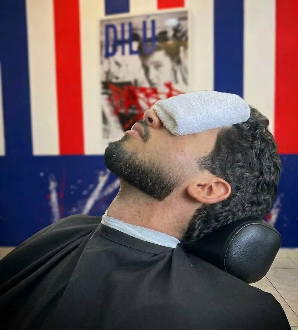 Cliente sul lavaggio con la salvietta calda sugli occhi prima della barba